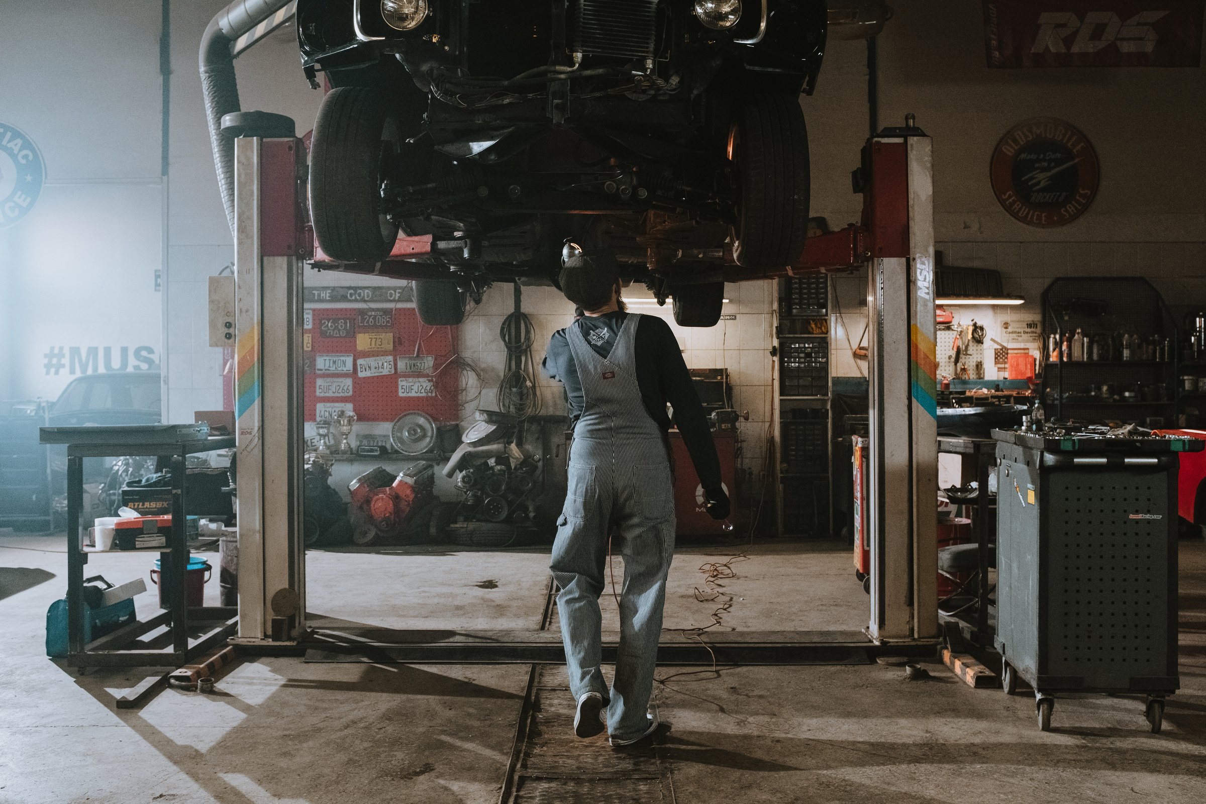 Man in Black T-shirt and Blue Denim Jeans Standing Near Black Car during Nighttime